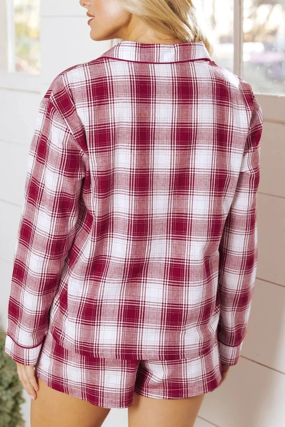 Back view of a woman wearing a red and white plaid long sleeve shirt and drawstring shorts lounge set