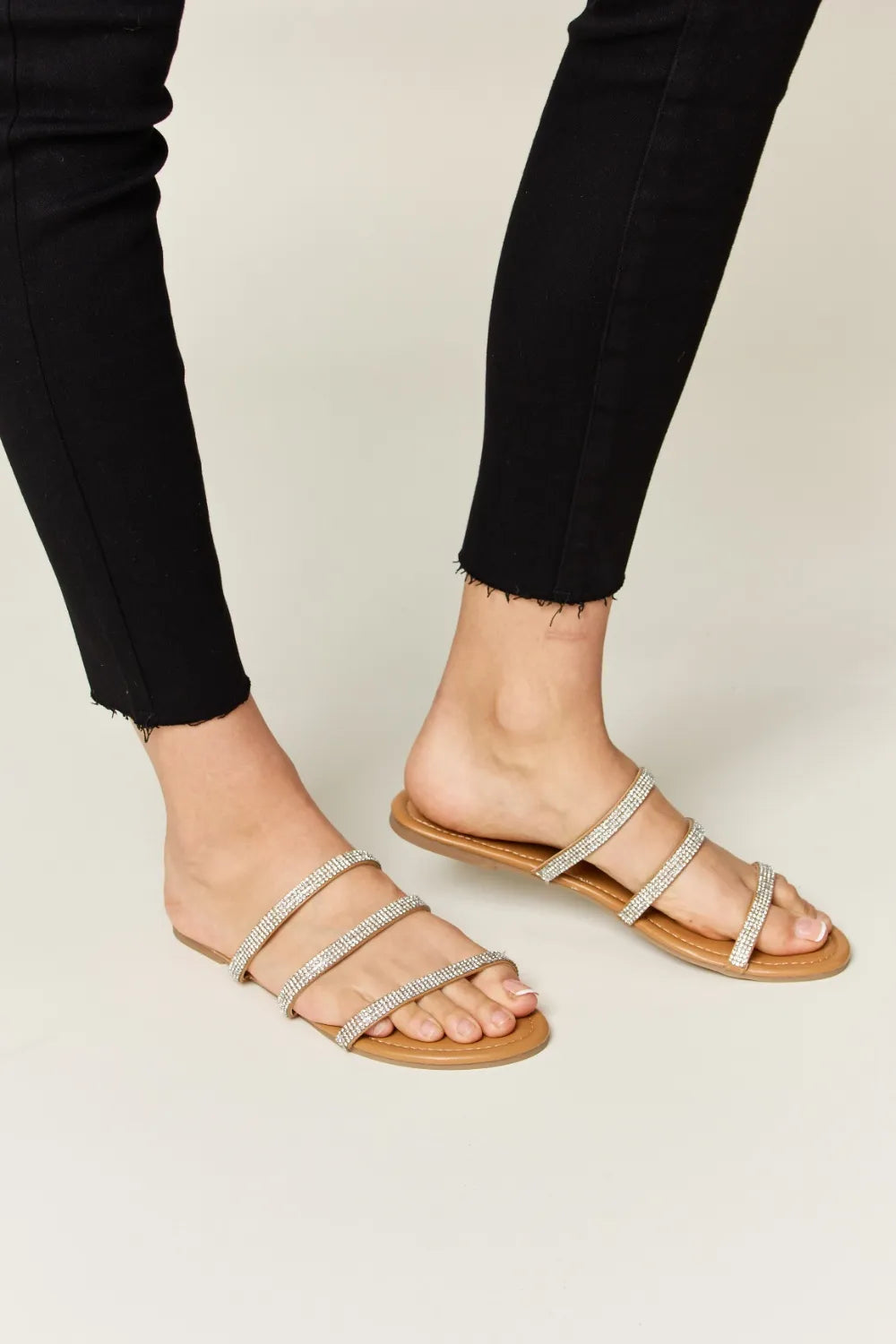 Rhinestone Three-Strap Flat Sandals on feet, paired with black jeans