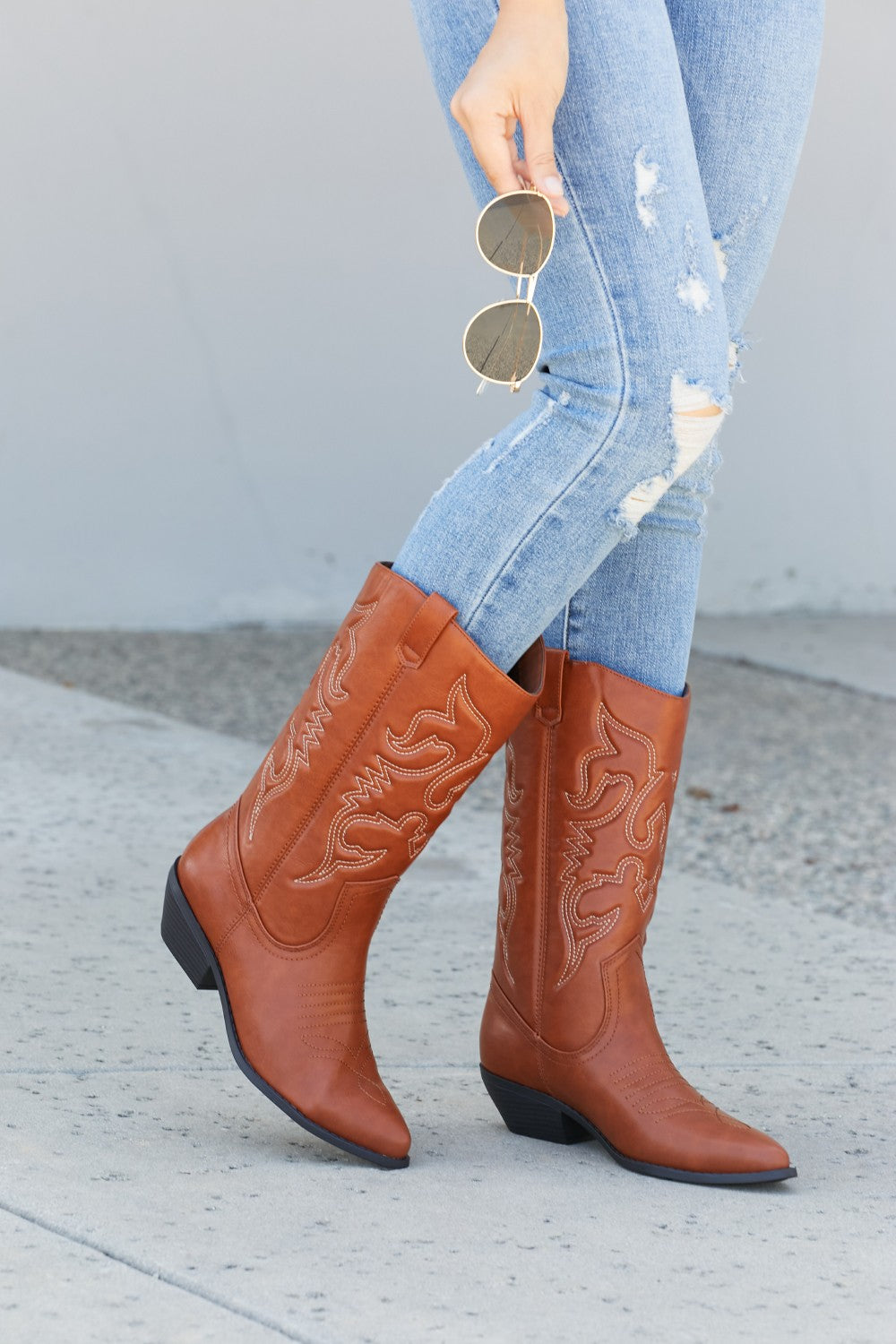 Embroidered Mid-Calf Cowboy Boots in brown with white stitching, worn with ripped blue jeans