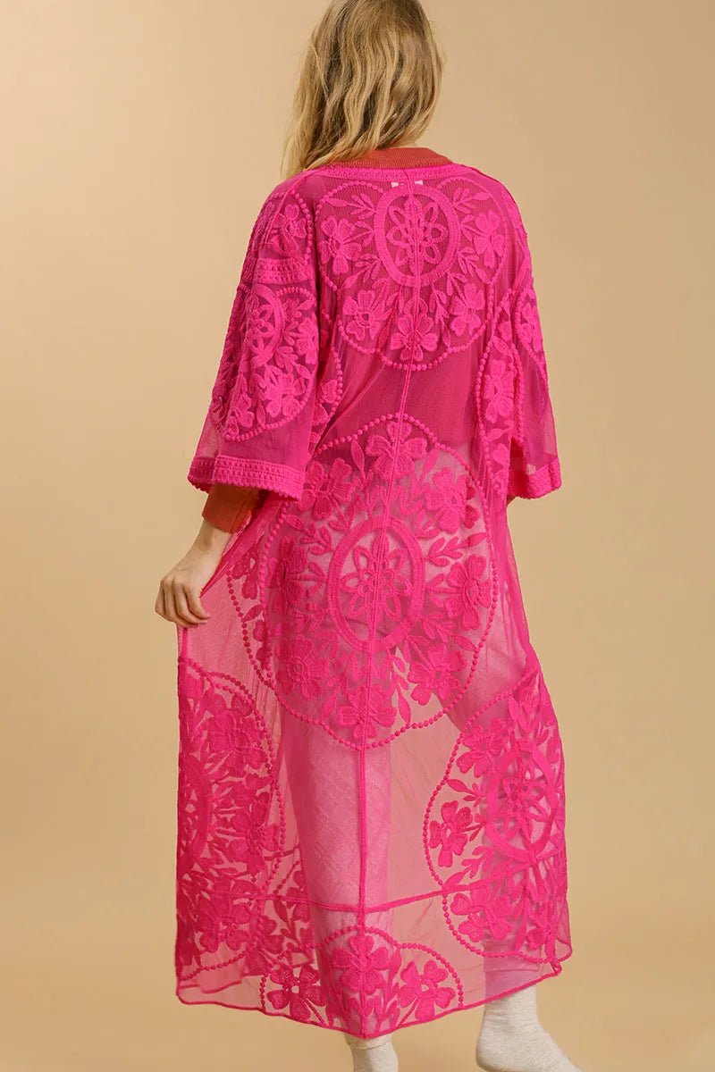 Back of a woman wearing a long, hot pink, floral lace kimono with a waist tie