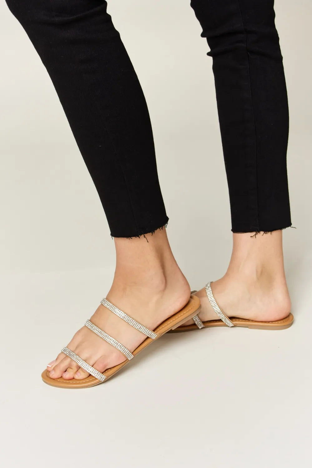 Rhinestone Three-Strap Flat Sandals on feet with black pants