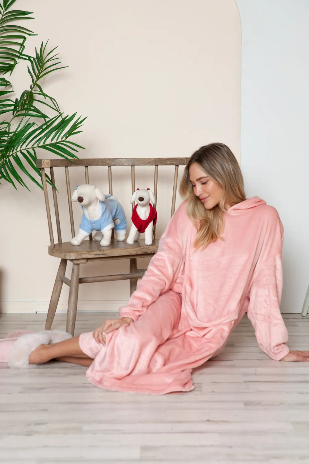 Woman in pink Double Take Full Size Pocketed Hooded Midi Lounge Dress with two stuffed dogs on a chair