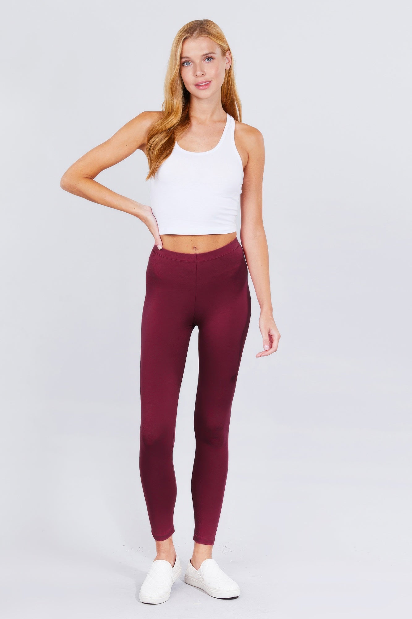 Blonde woman wearing a white crop top and maroon spandex leggings