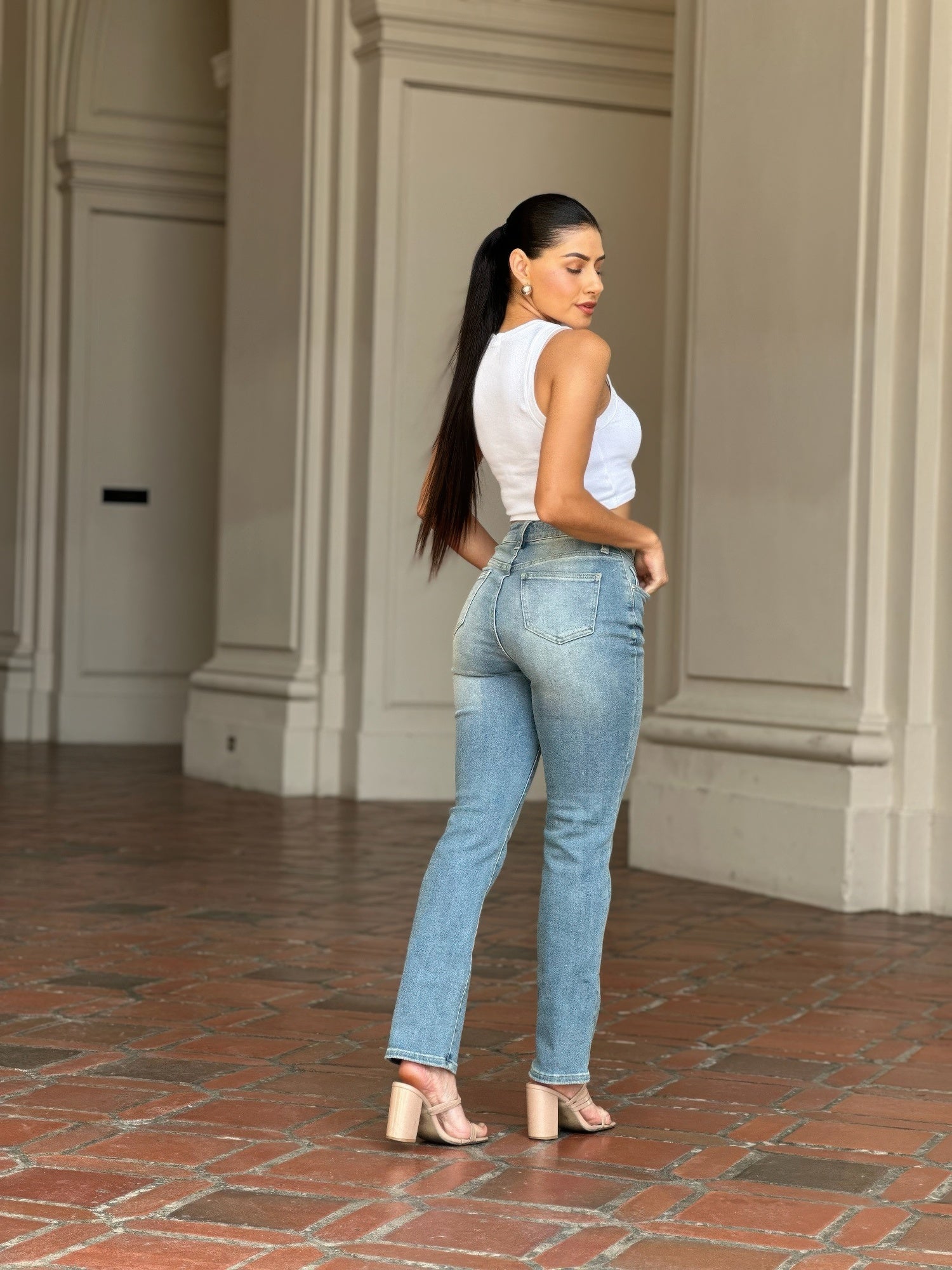 Woman in High Rise Cigarette Button Fly Straight Jeans and white top, looking over her shoulder
