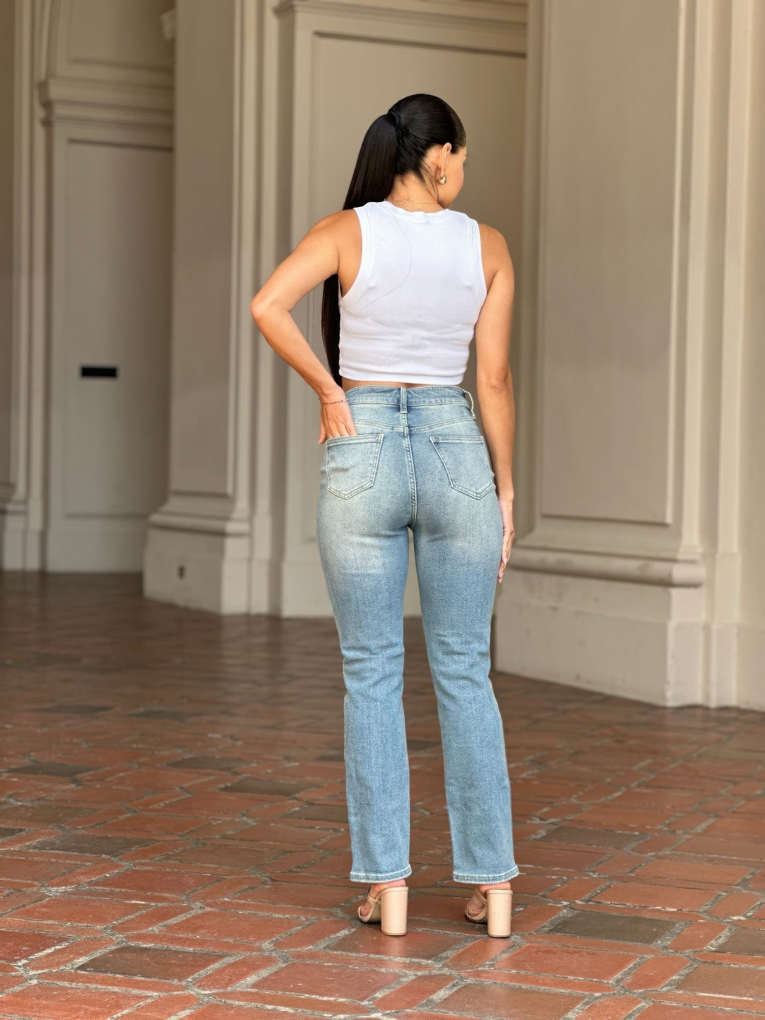 Woman from behind wearing High Rise Cigarette Button Fly Straight Jeans and a white tank top