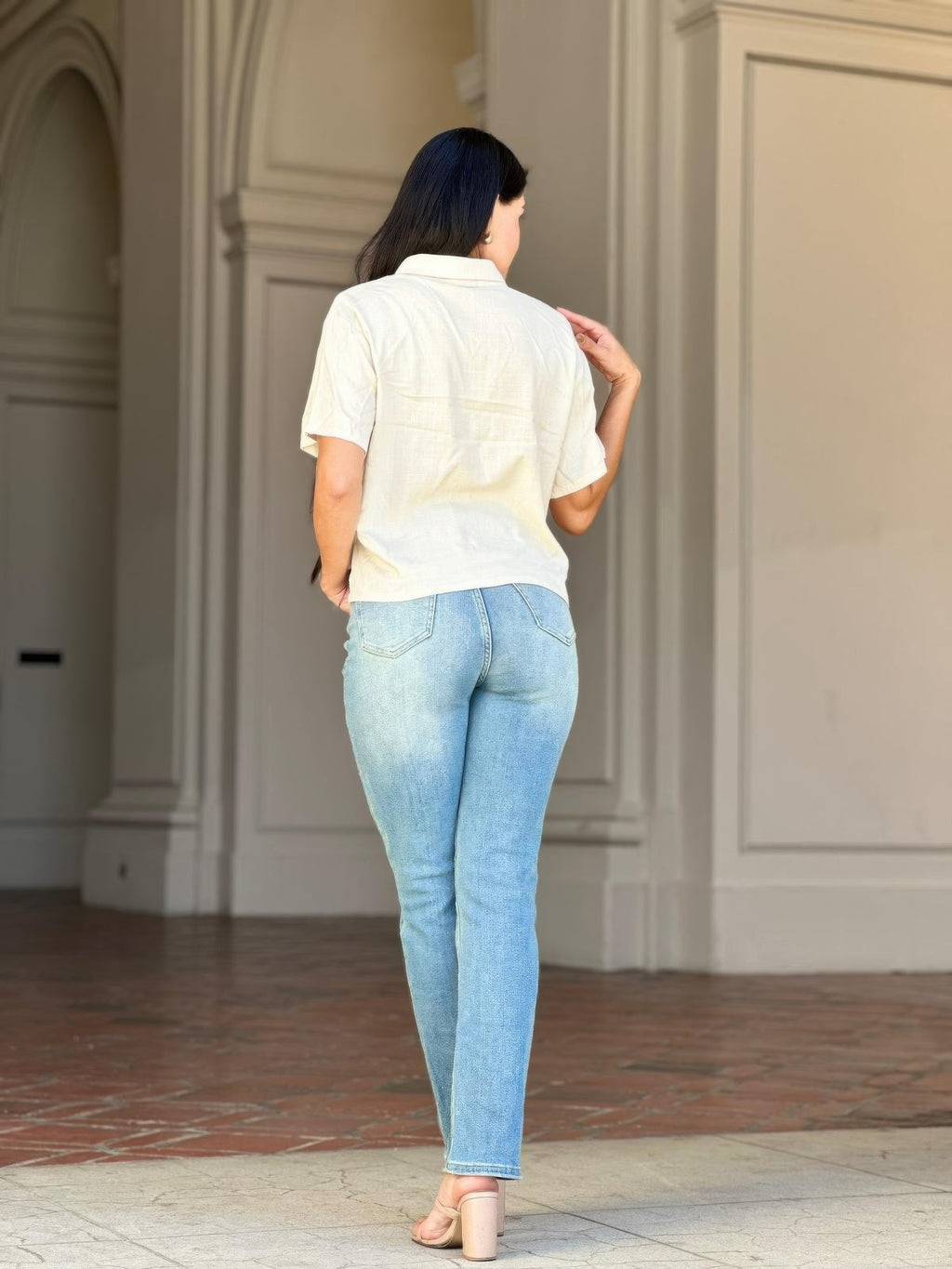 Woman from behind wearing High Rise Cigarette Button Fly Straight Jeans and a light-colored top