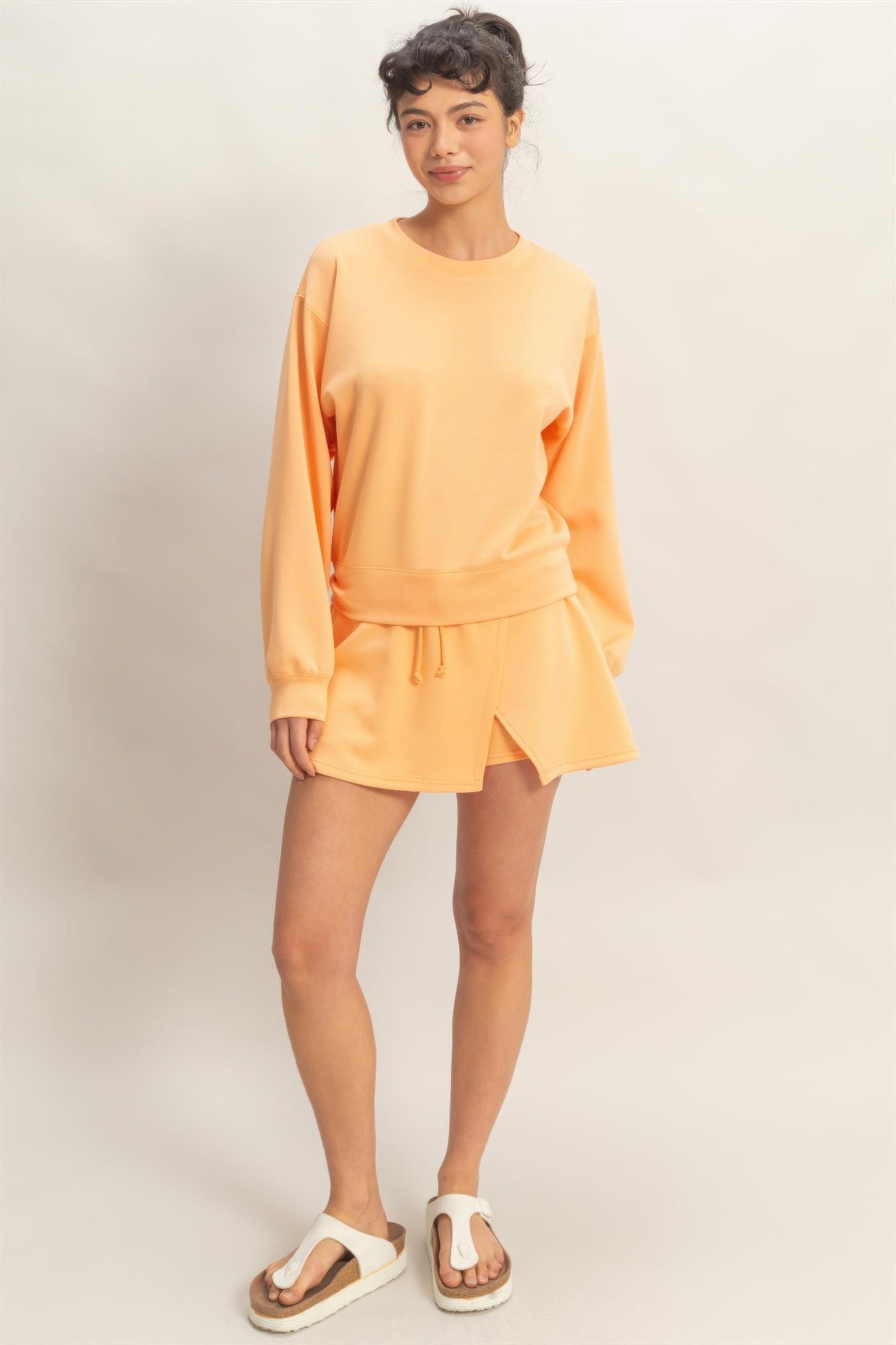 Apricot Nectar Wrap Skort and matching sweatshirt on a model