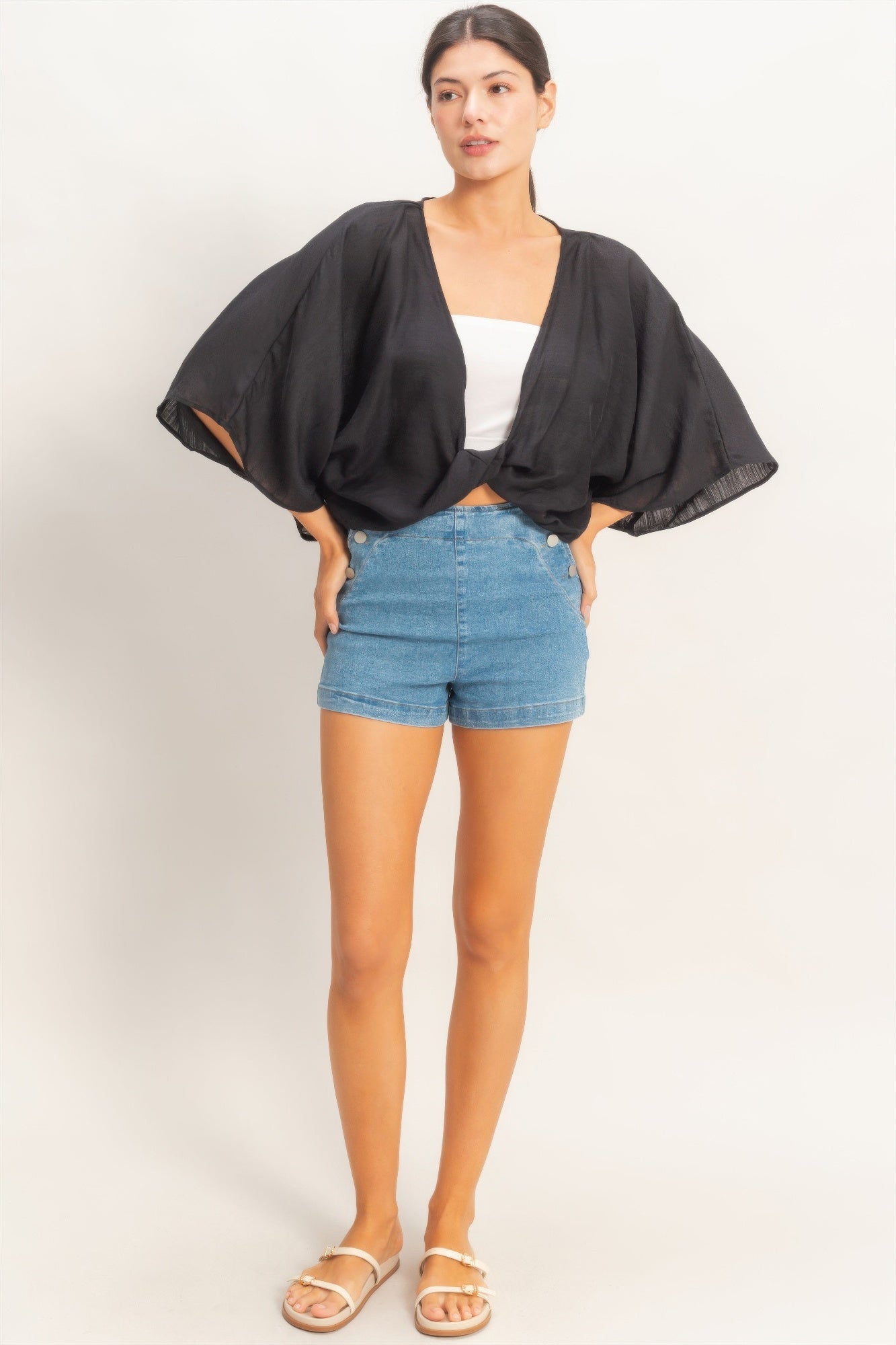 Ink Black Twist-Front Draped Shrug Top worn over a white bandeau and denim shorts