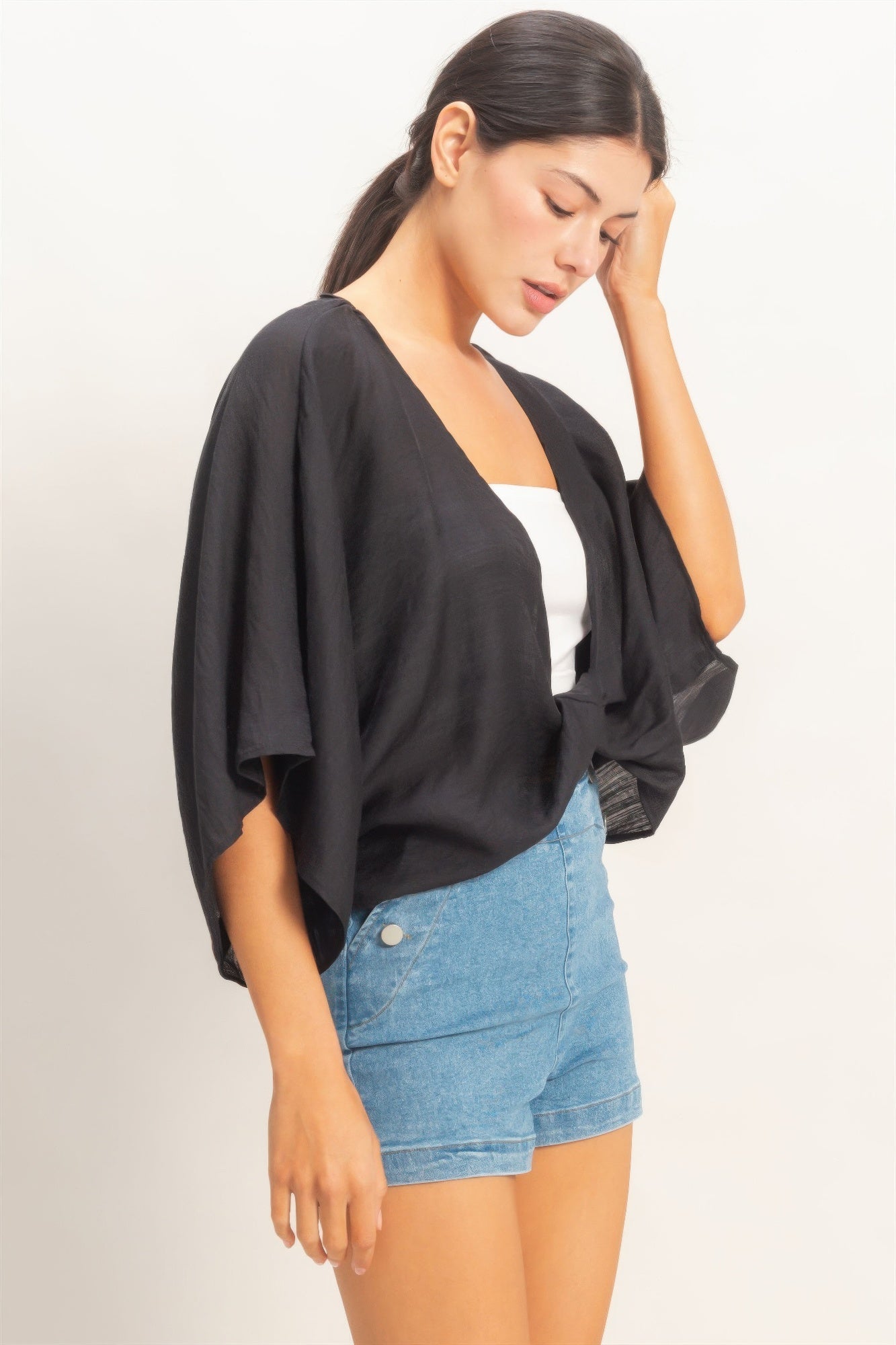 Ink Black Twist-Front Draped Shrug Top worn over a white top and denim shorts