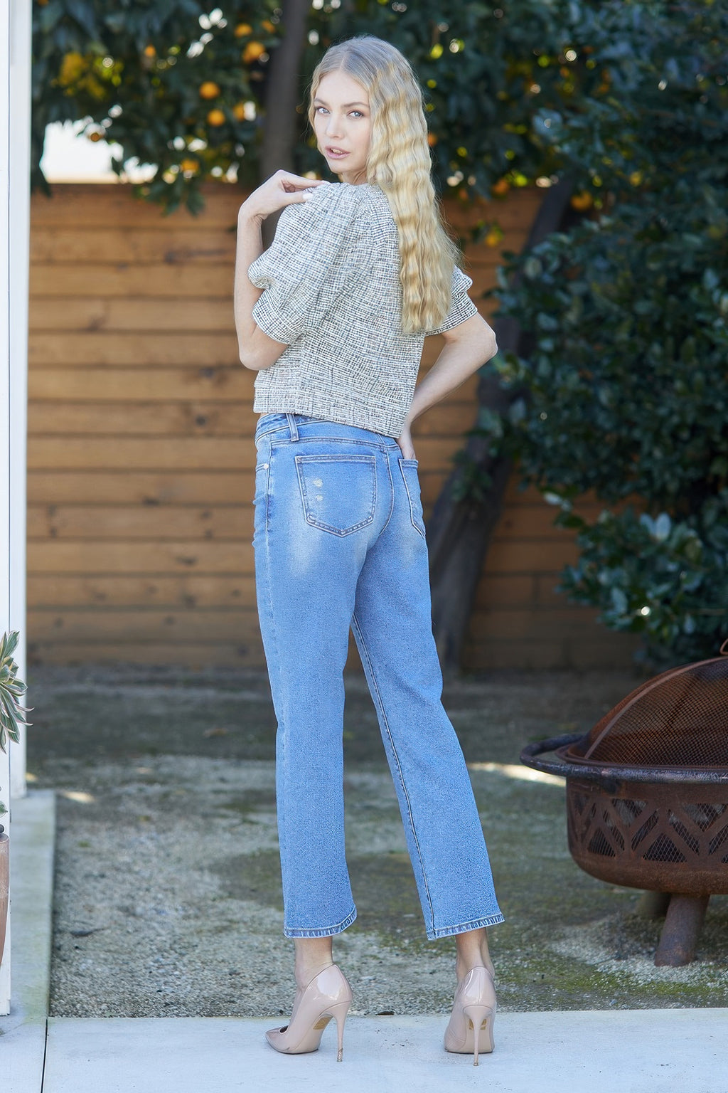 Woman wearing Mid Rise Crop Slim Bootcut Jeans with Stretch, light wash, with a patterned top and heels