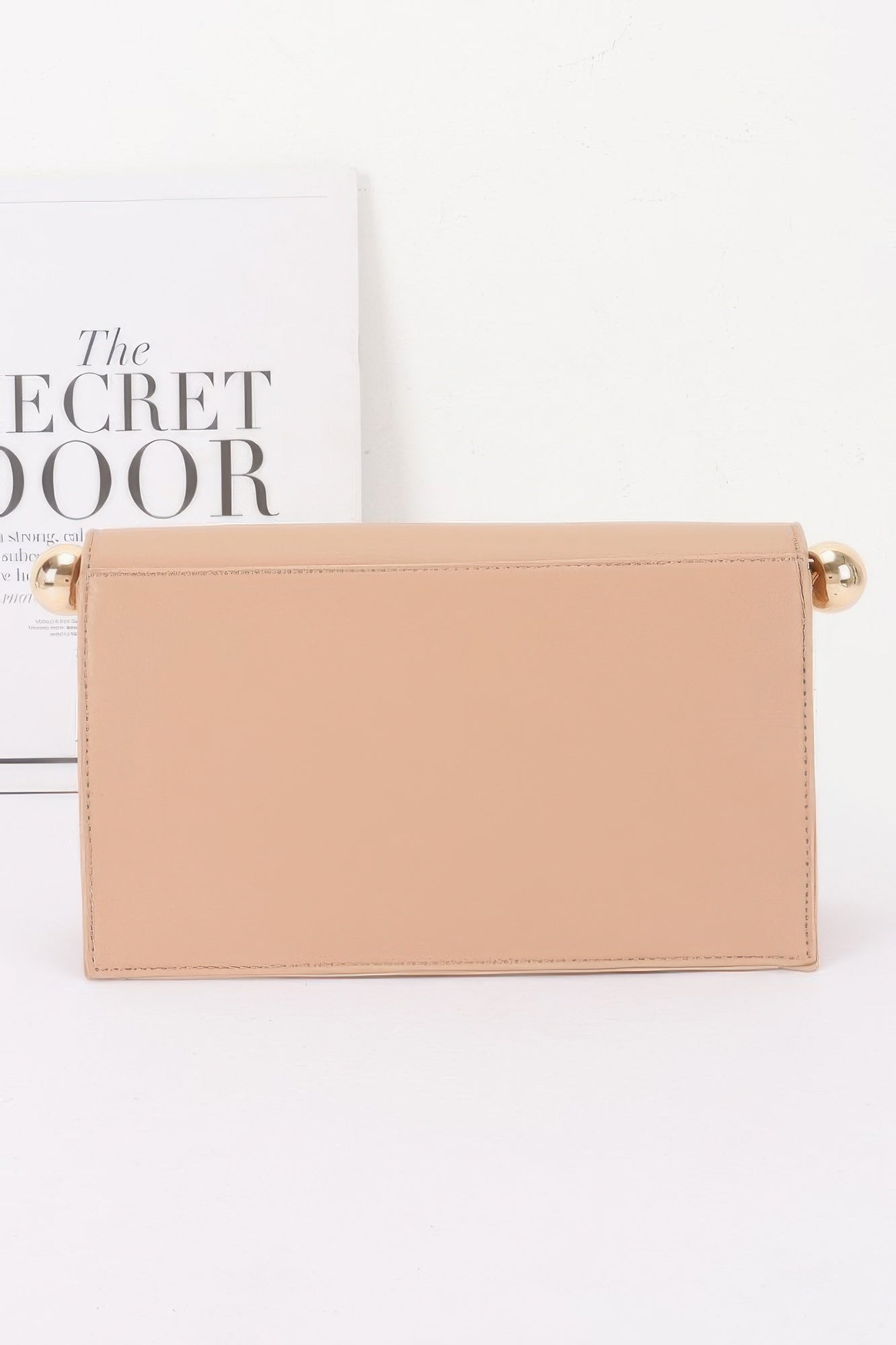 Roll-top Sphere Accent Chain Clutch in a light beige color with gold sphere accents