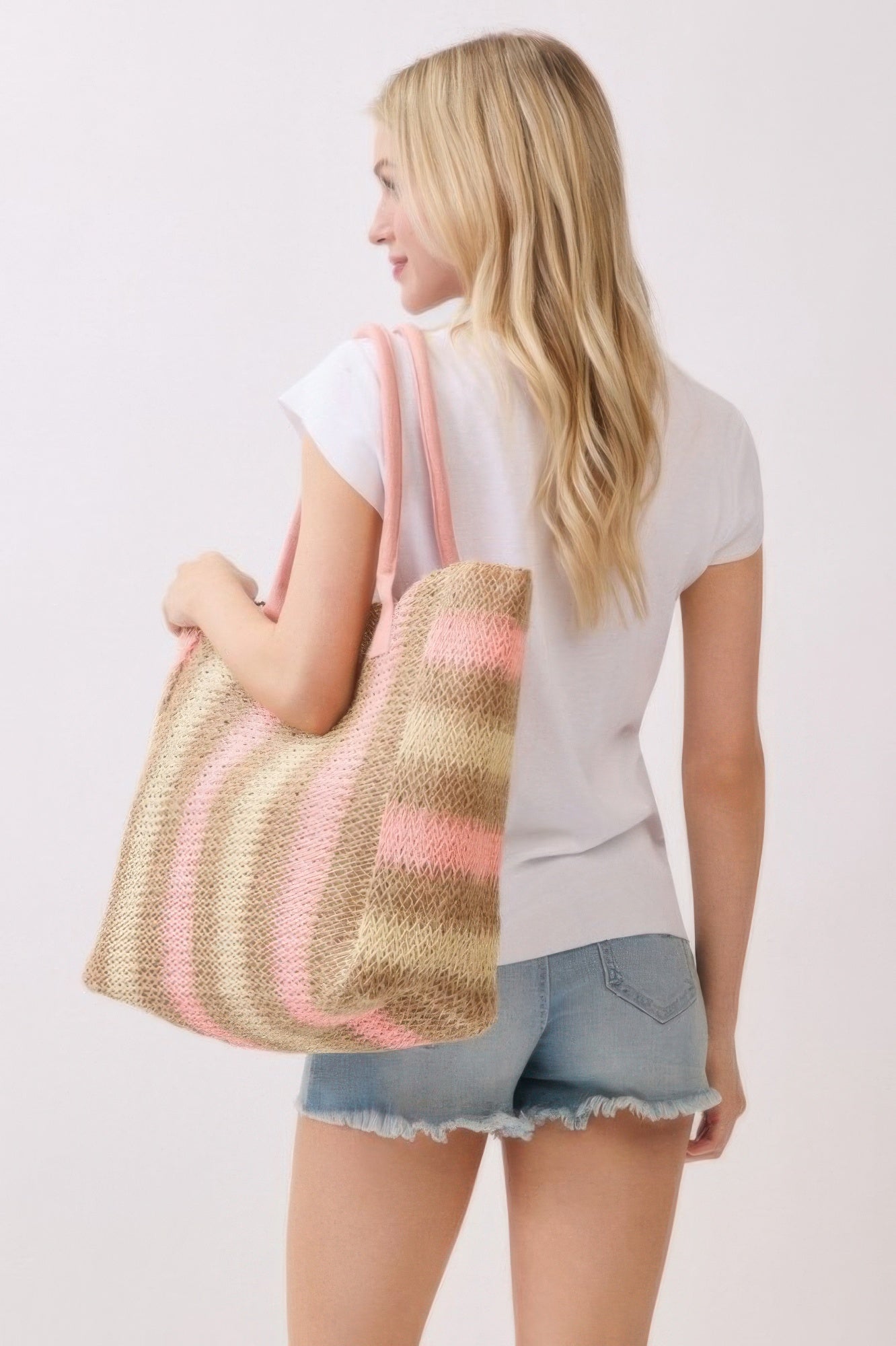 Blonde woman in white t-shirt and denim shorts carrying a Natural Brown Multi Color Stripe Straw Tote Bag