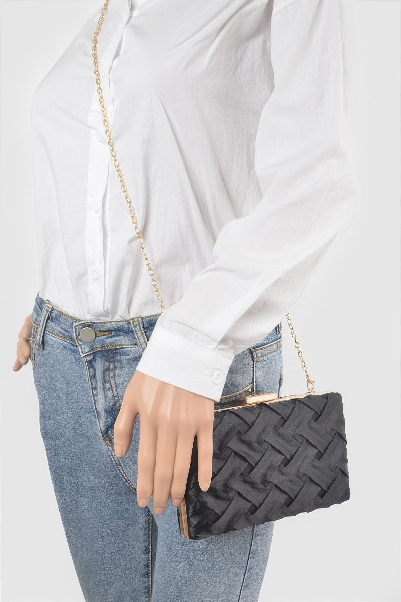 Cross Hatched Chain Clutch in black with gold chain and clasp, held by a person in a white shirt and jeans