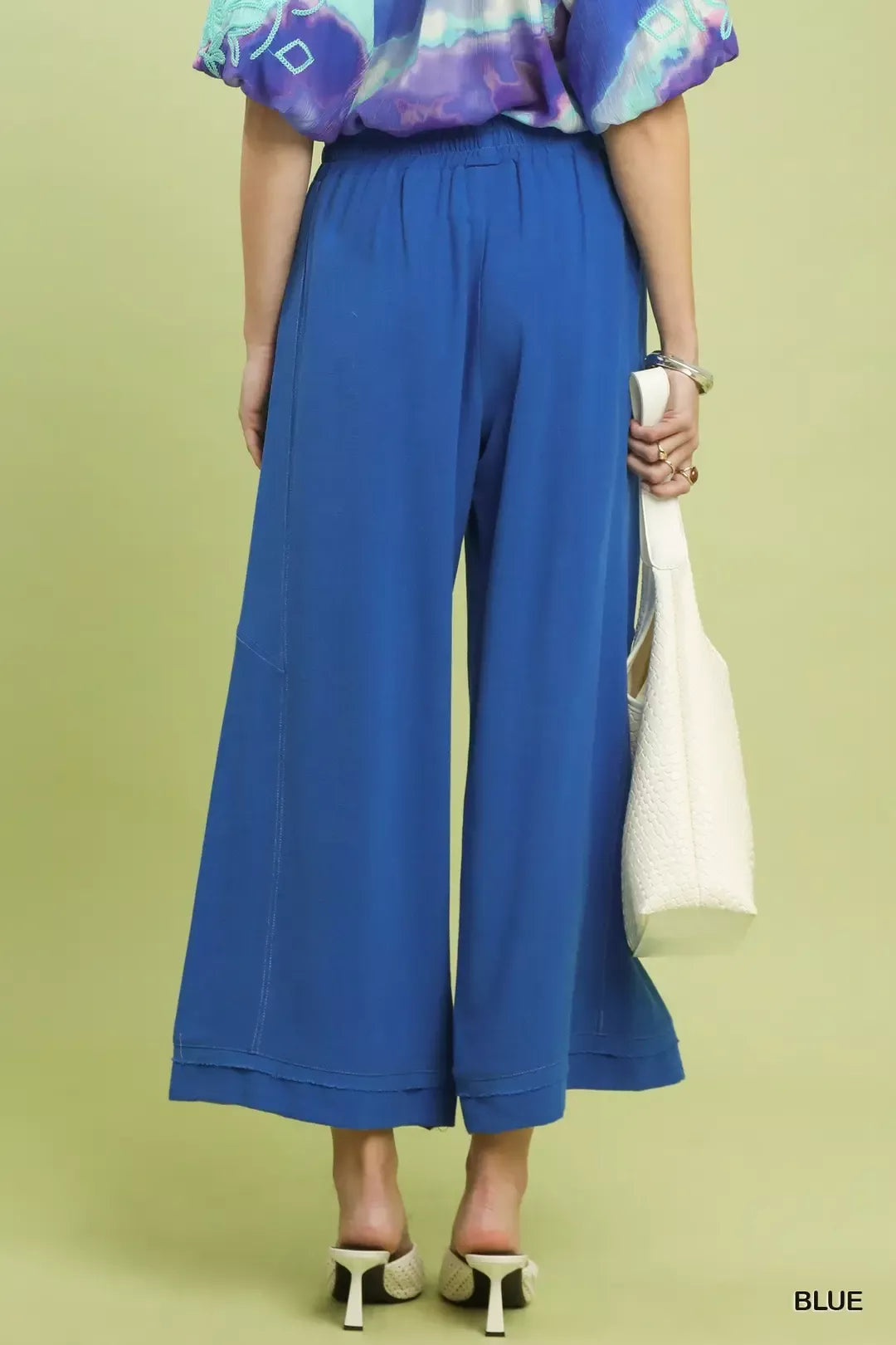 Woman from behind wearing Cobalt Horizon Elastic-Waist Wide-Leg Pants and holding a white handbag