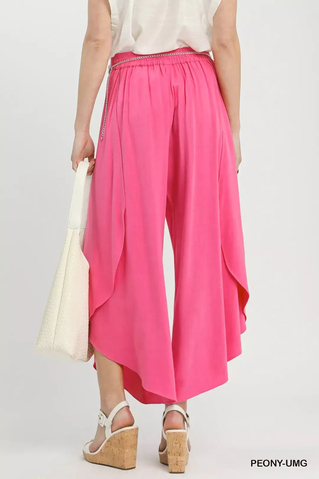 Petal Glow Asymmetrical Hem Wide-Leg Pants in bright pink with a silver chain belt and white wedge sandals
