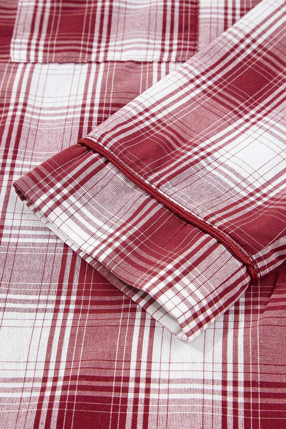 Close up of the cuff of a red and white plaid long sleeve shirt