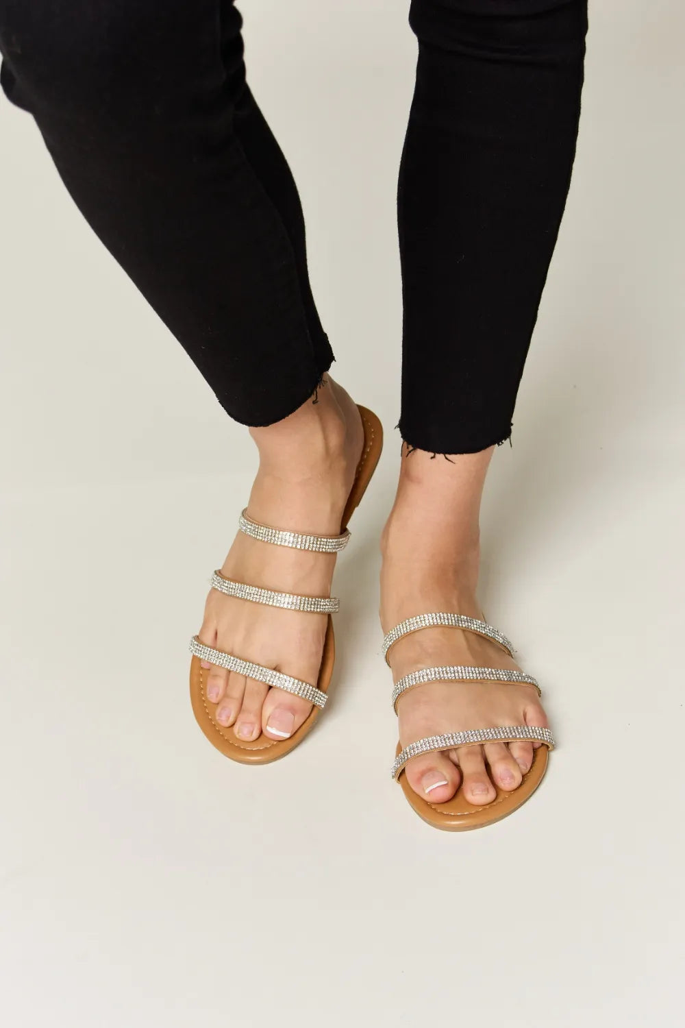 Rhinestone Three-Strap Flat Sandals on feet with black pants