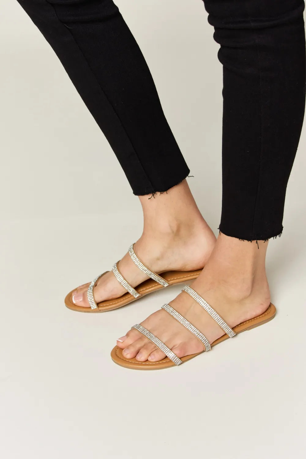 Rhinestone Three-Strap Flat Sandals on feet with black pants
