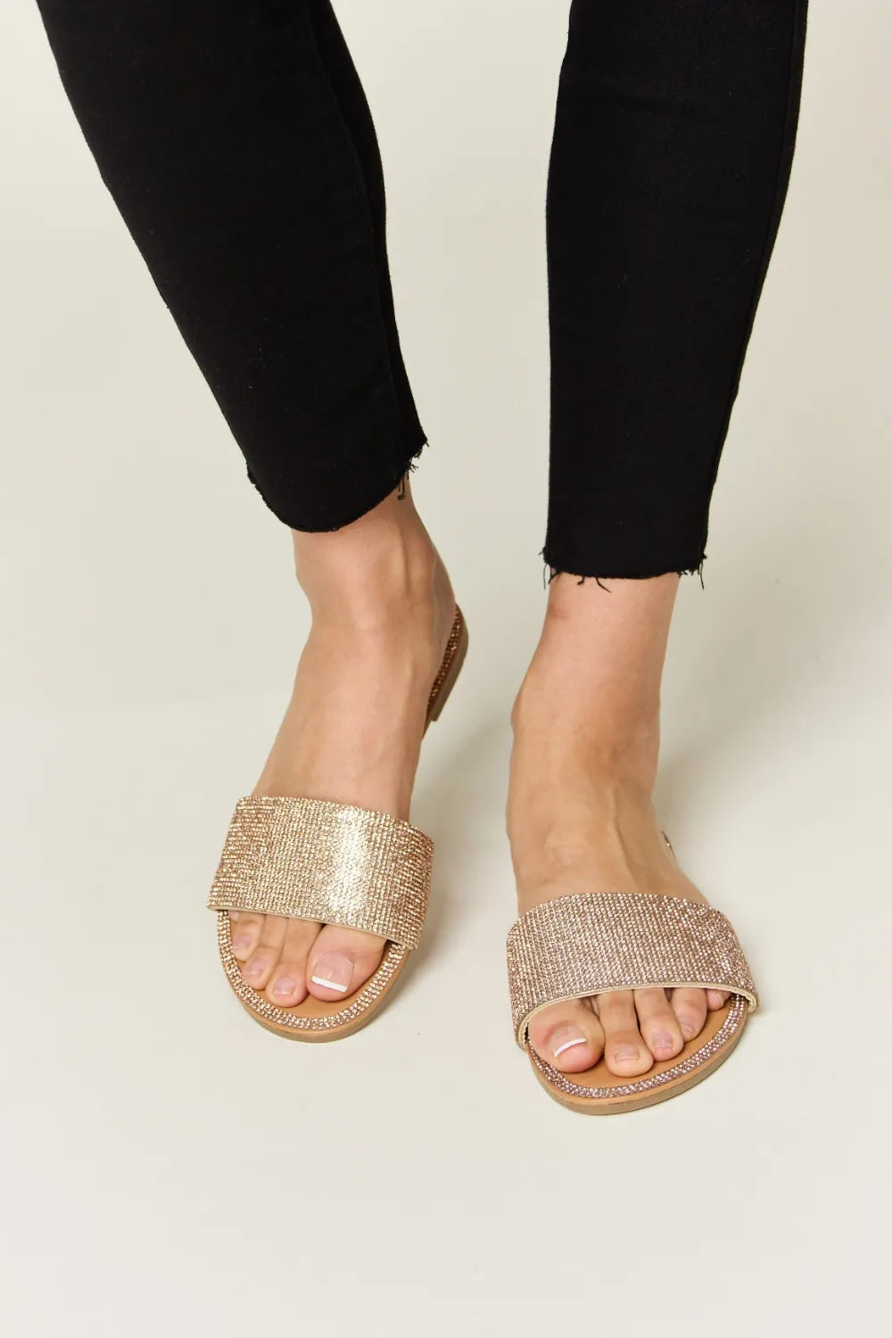 Rhinestone Open Toe Flat Sandals in rose gold, worn by a model with black pants